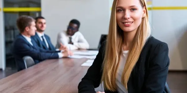 A woman sitting at the head of a table in front of two other people.